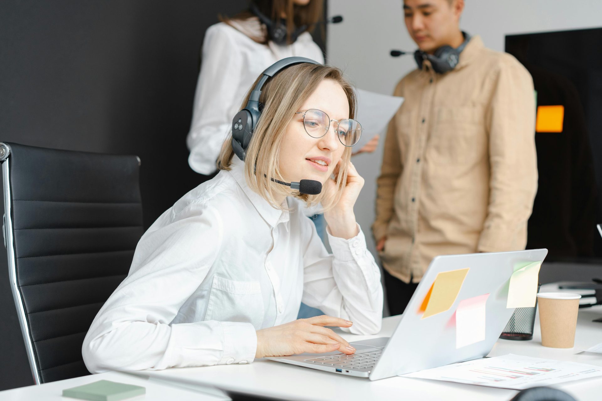 Customer support professionals working with headsets and laptops in a modern office environment.